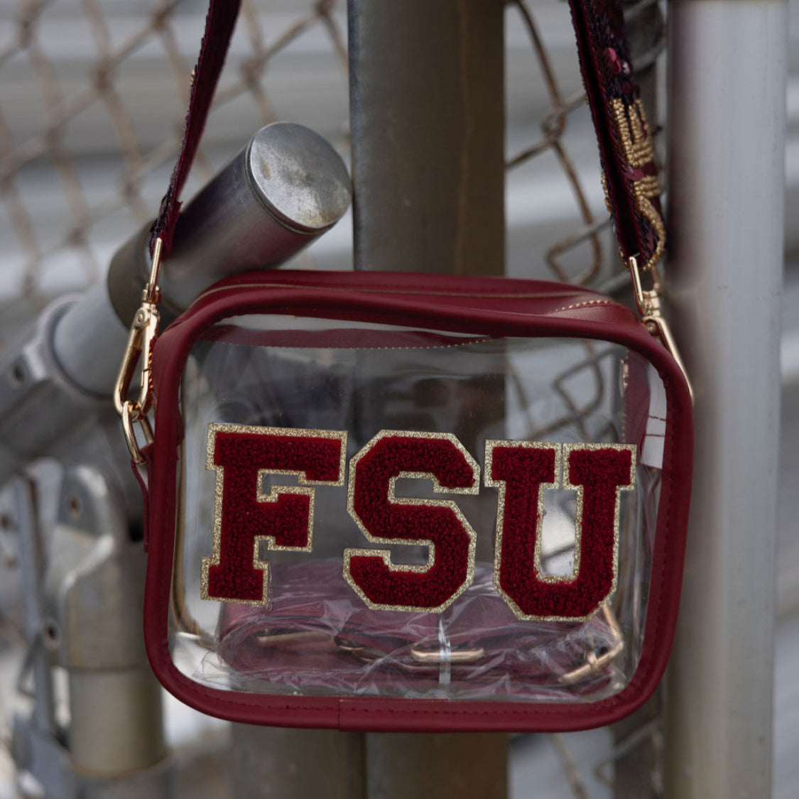 Clear bag with red 'FSU' letters hanging on a metal fence.