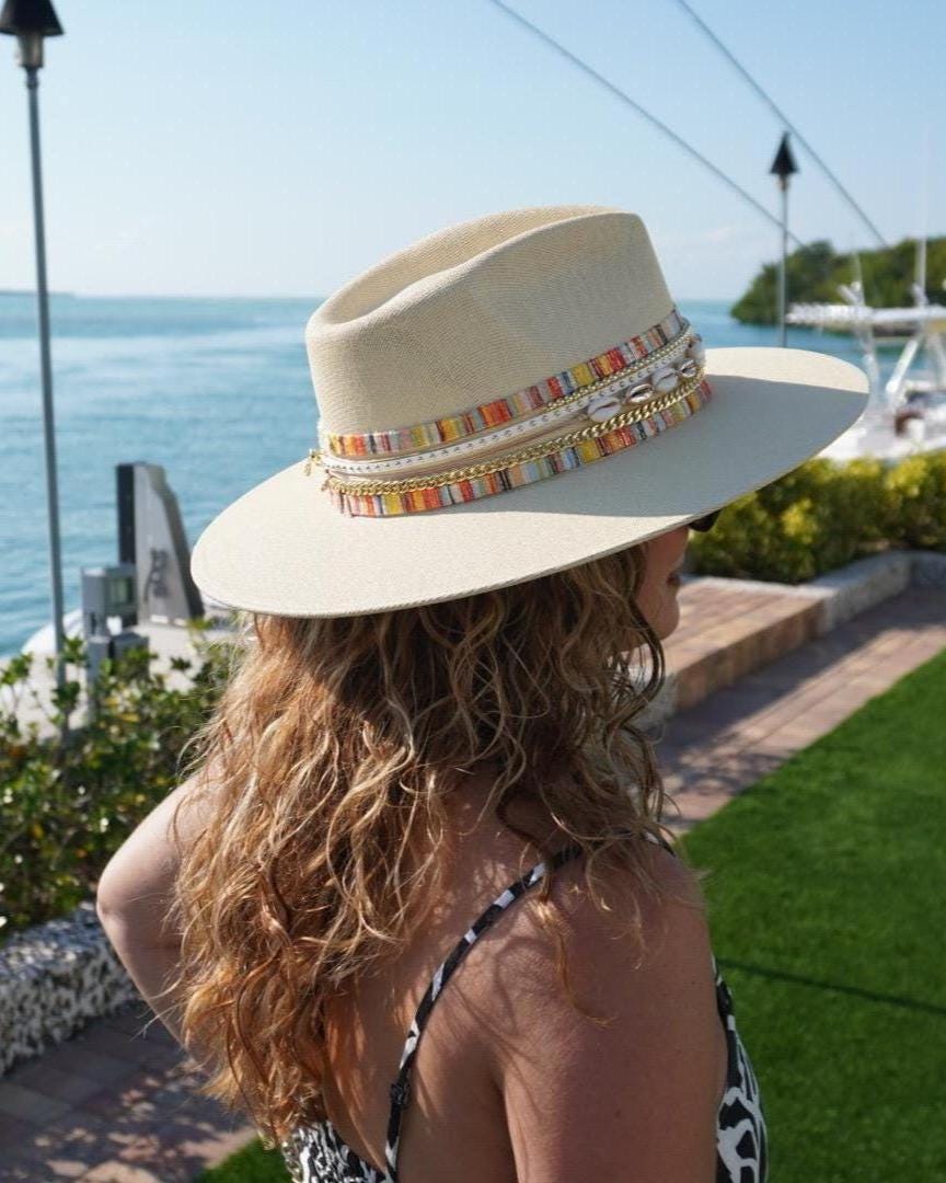 Women’s waterproof boater hat by Sunkissed by Chrissy featuring a wide brim, straw material, jute band, and gold embellishments.