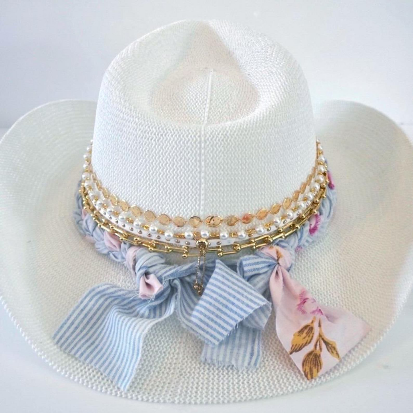 White cowboy hat by Sunkissed by Chrissy featuring a jeweled bow, coquette style embellishments, perfect for vacation or resort wear.