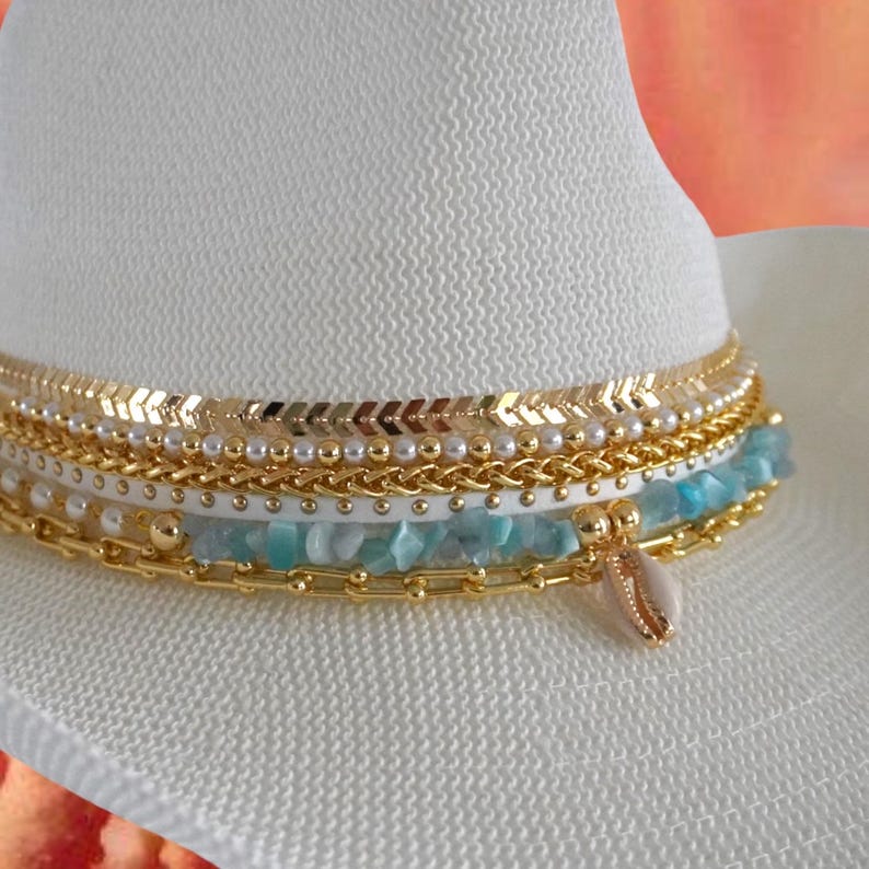 White straw cowgirl beach hat with shells and gold jewelry accents, perfect for summer resortwear and coastal boho style.
