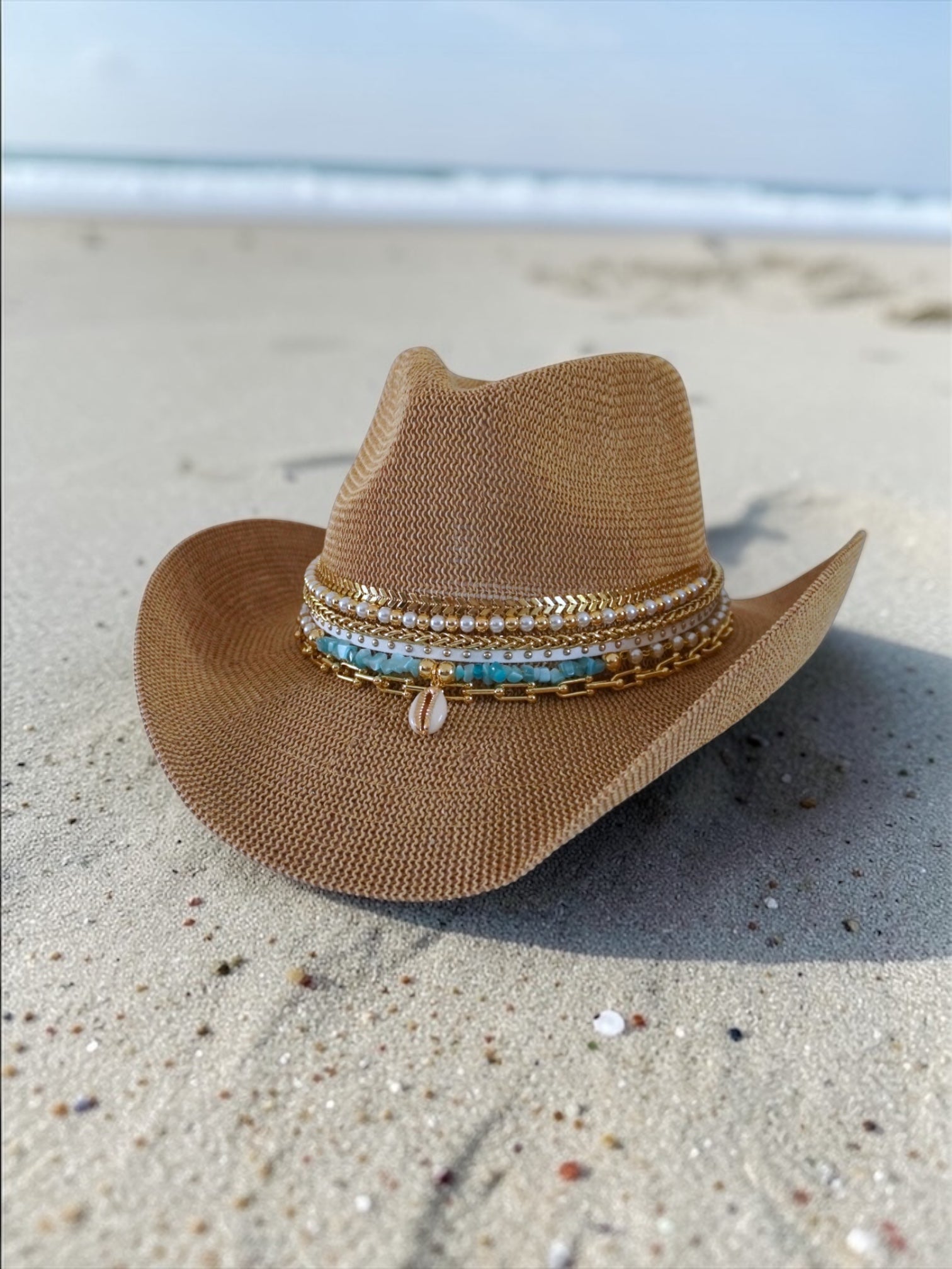 Luxury white cowgirl beach hat from Sunkissed by Chrissy, featuring shells, gold jewelry accents, and straw boho style for summer resortwear.